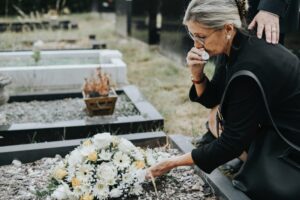 Old woman laying flowers on a grave